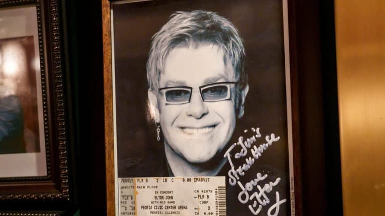 A signed portrait of legendary rock star Elton John with a ticket to his 2011 show at the Peoria Civic Center is framed on a