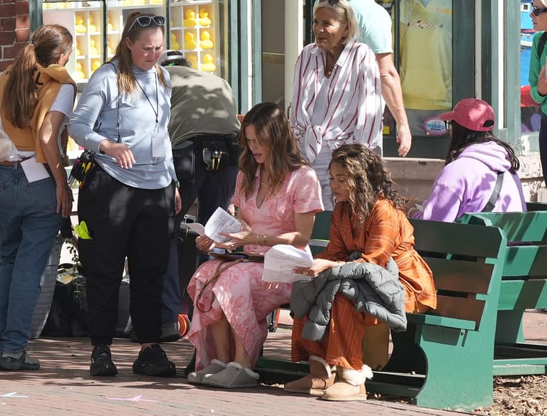 Actresses Jennifer Garner and Regina Hall sit on a bench in front of TownPool on Main Street during a break in filming. Filming
