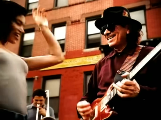 Carlos Santana entertains a lady friend in the music video to Smooth ft. Rob Thomas